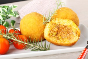 Arancini, rice balls with meat and sauce on complex background