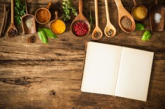 Blank cookbook and spices on wooden table
