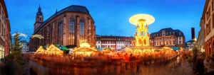 Christmas market in Heidelberg, Germany, a panorama shot at dusk showing illuminated kiosks, historic architecture and blurred people